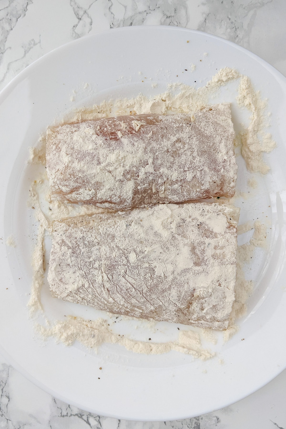 Top view of two fish fillet covered with all purpose flour.