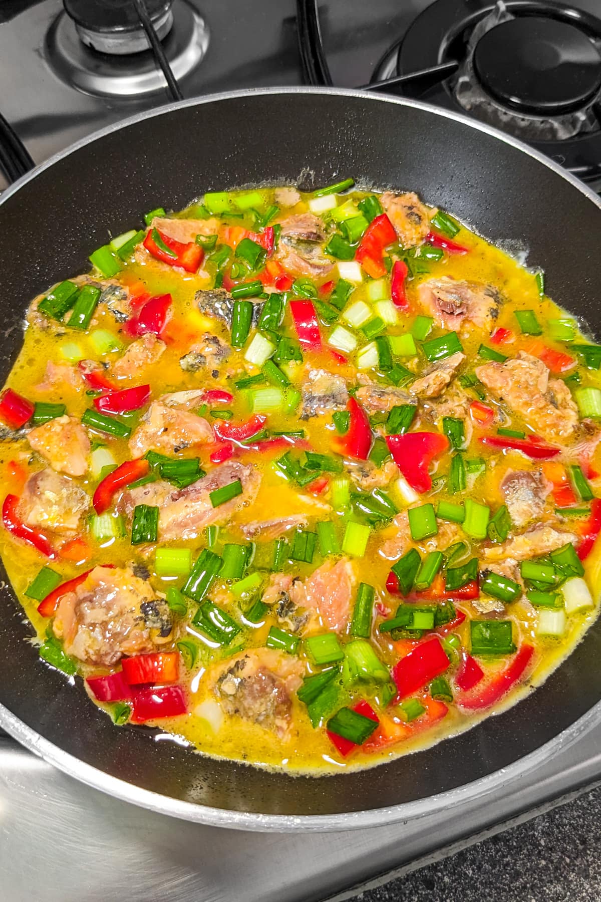 Sardine omelette with different veggies in a frying pan.