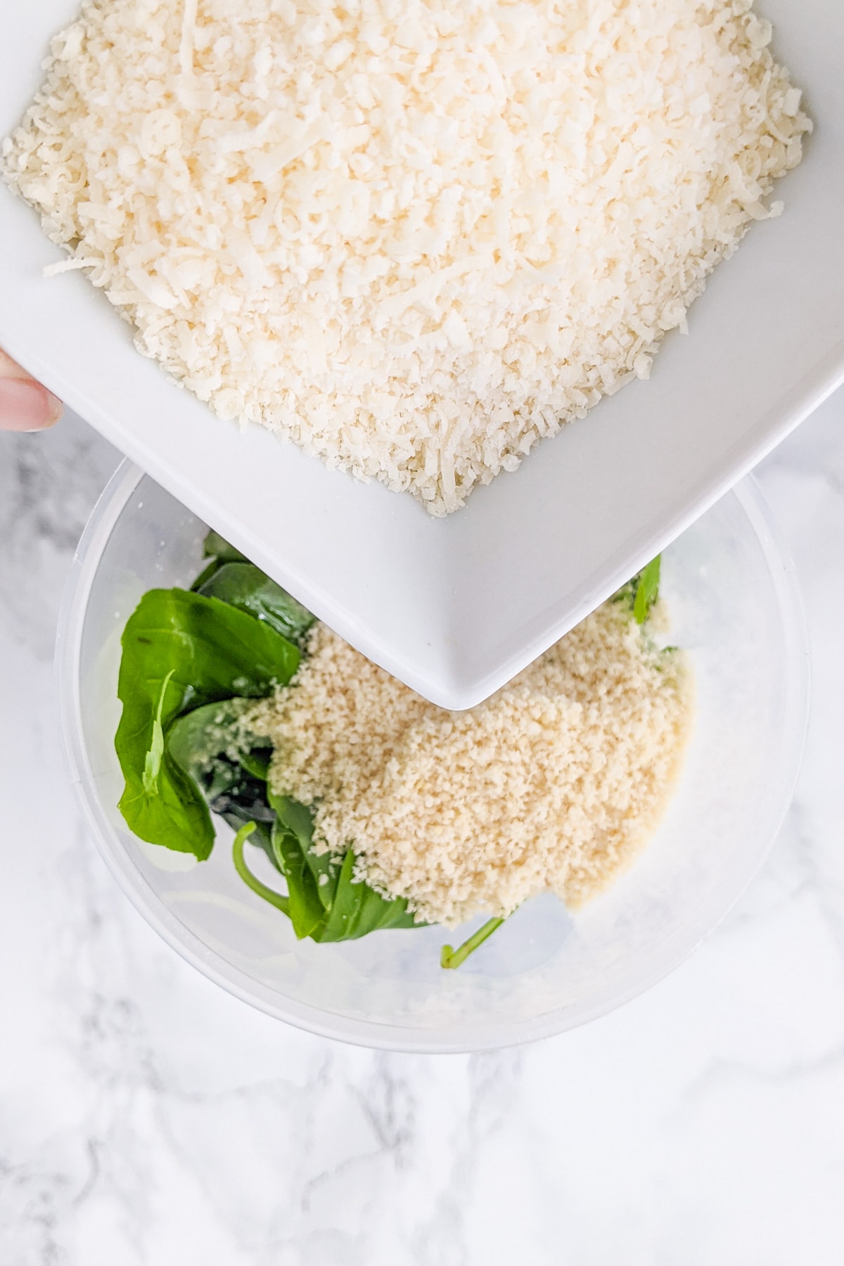 Close look of a plate with shredded parmesan over a bowl with basil and almond flour.
