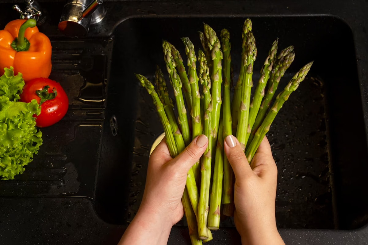 Woman hands holding raw asparagus over a dark room.