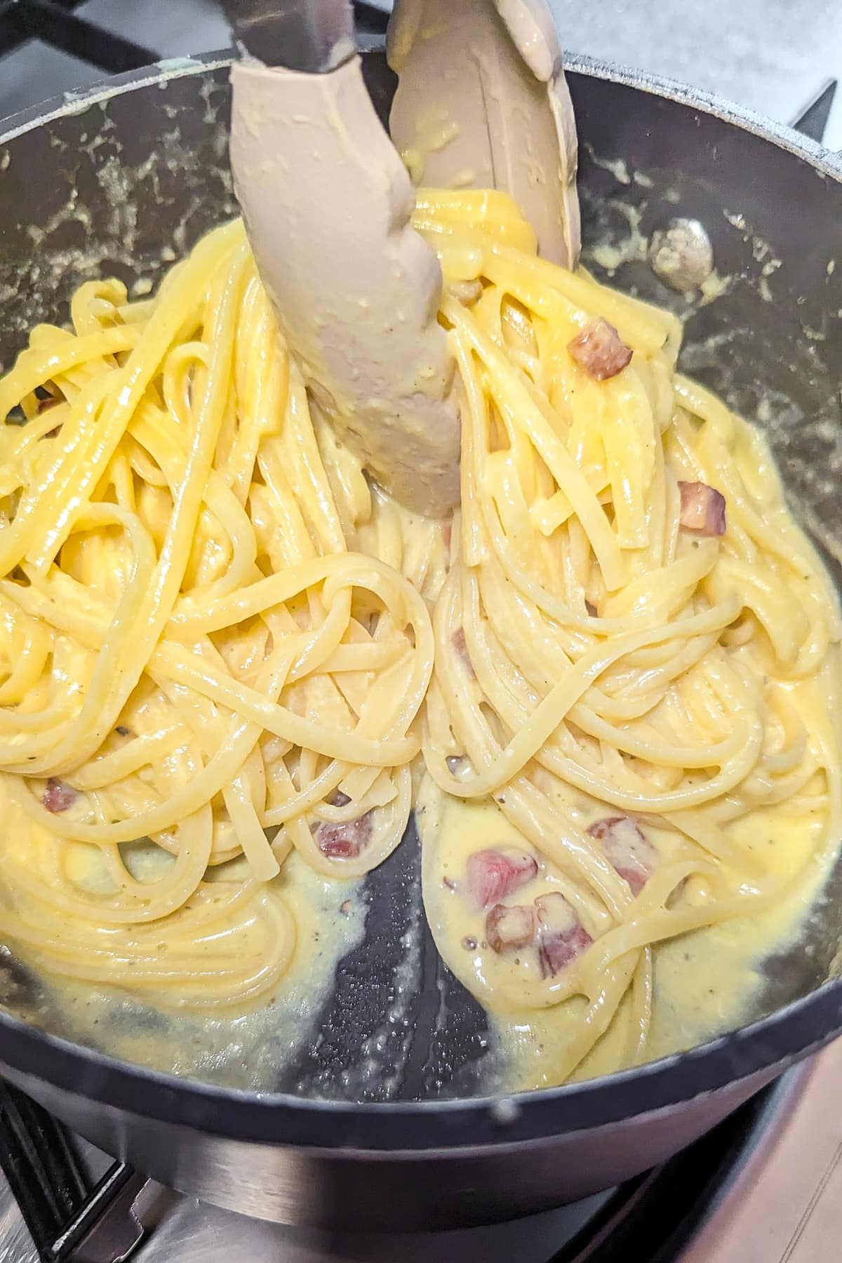 Creamy carbonara pasta with bacon in a saucepan.