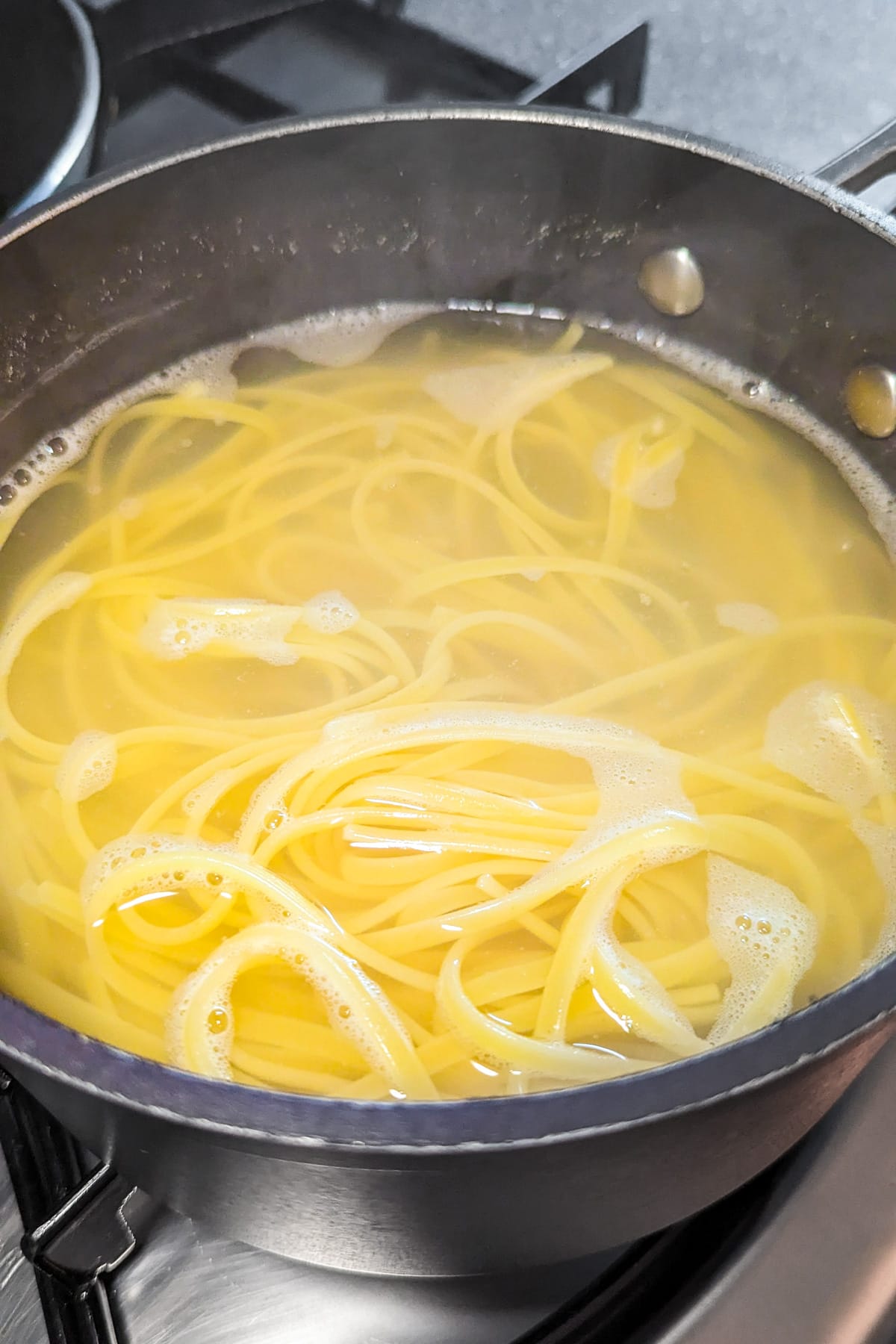 Boiling spaghetti on the stove in a large saucepan.
