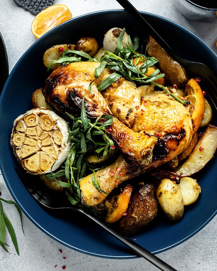 Top view of a festive table with roasted chicken, garlic and potatoes.