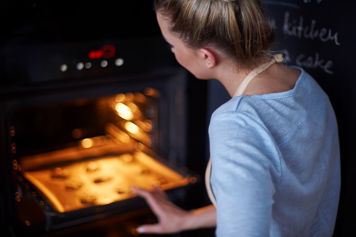 A woman looking in the oven.