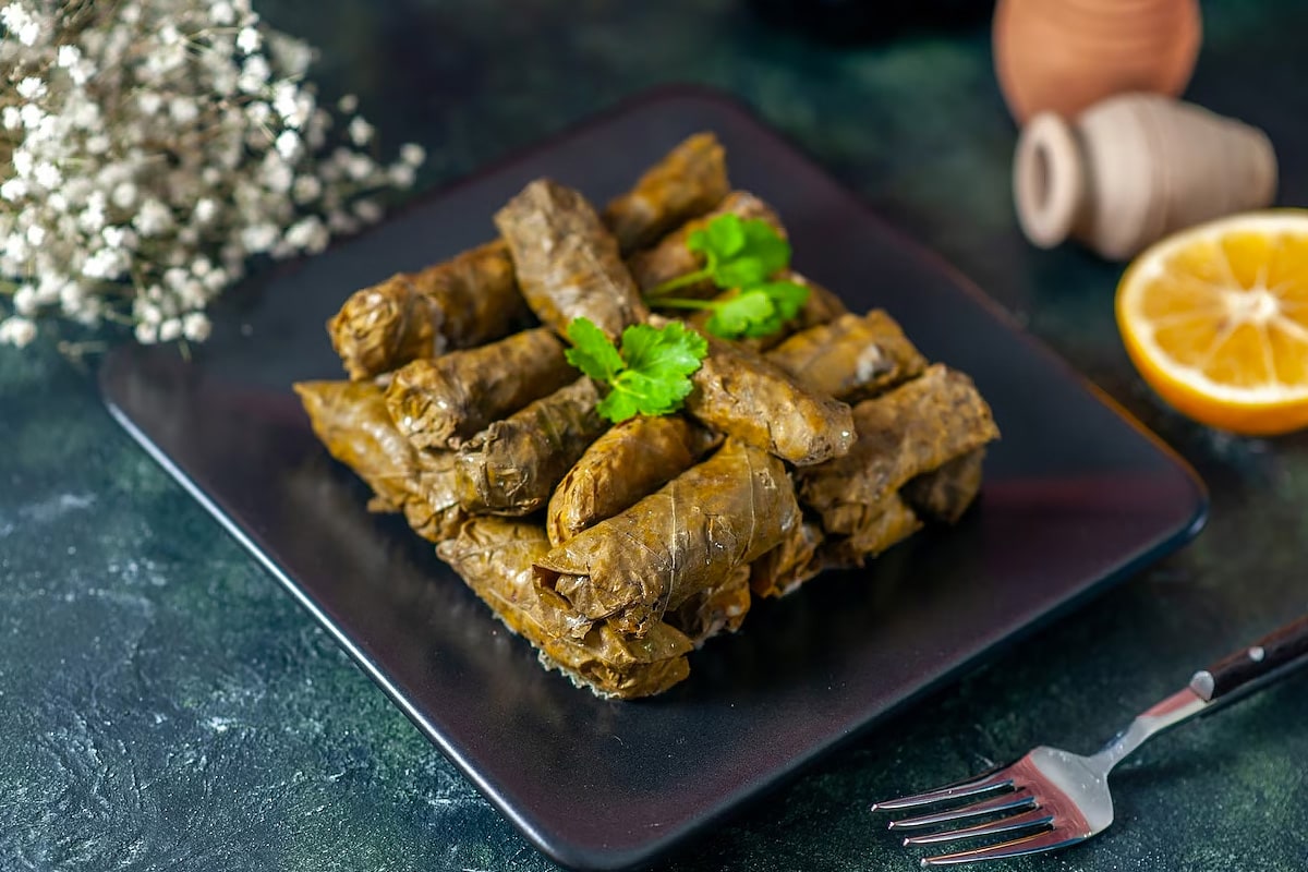 Black plate with dolmas and parsley leaves.