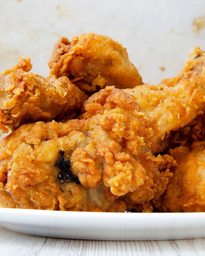 Close look of fried drumsticks sitting in a white plate.