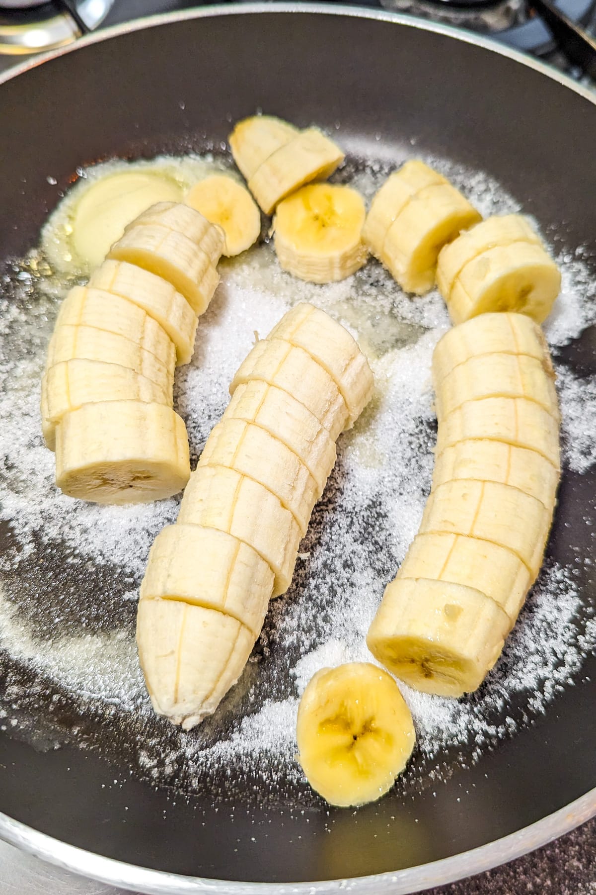 Close look of caramelizing banana in a frying pan full with sugar.