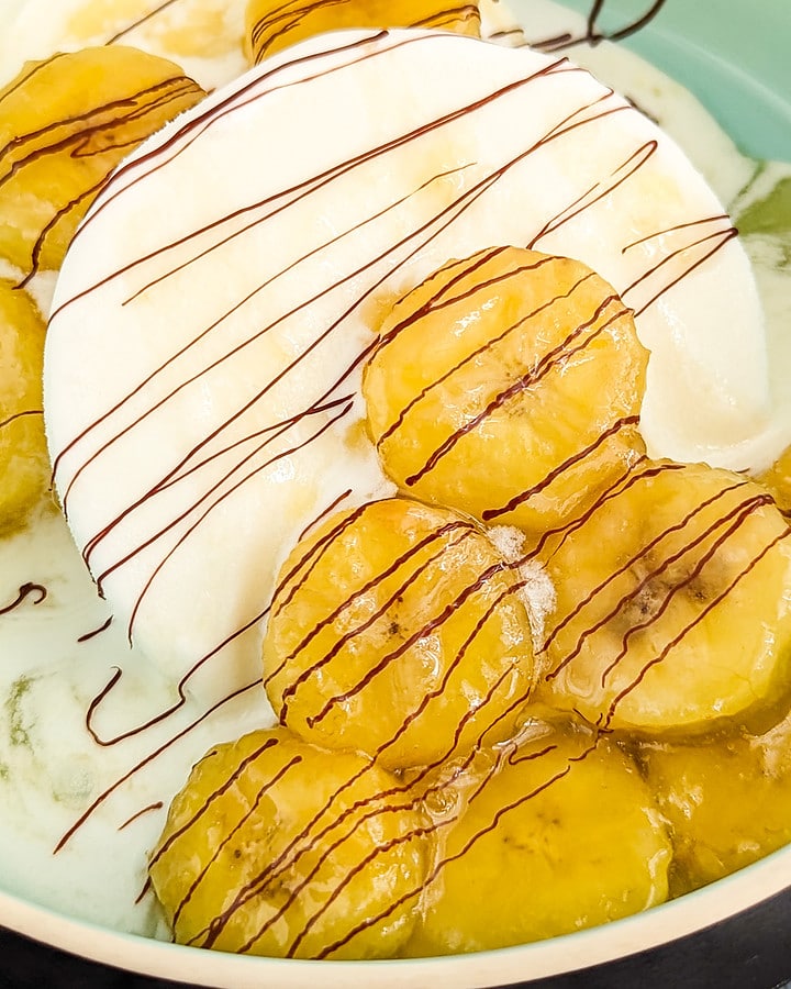 Close look of fried banana ice cream decorated with chocolate lines.