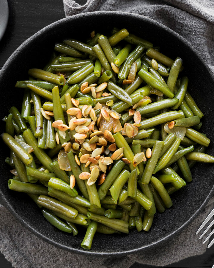 Top view of a black plate with roasted green beans.