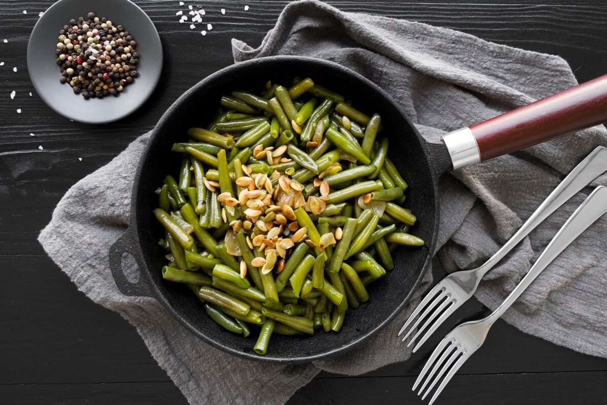 Top view of a black plate with roasted green beans.