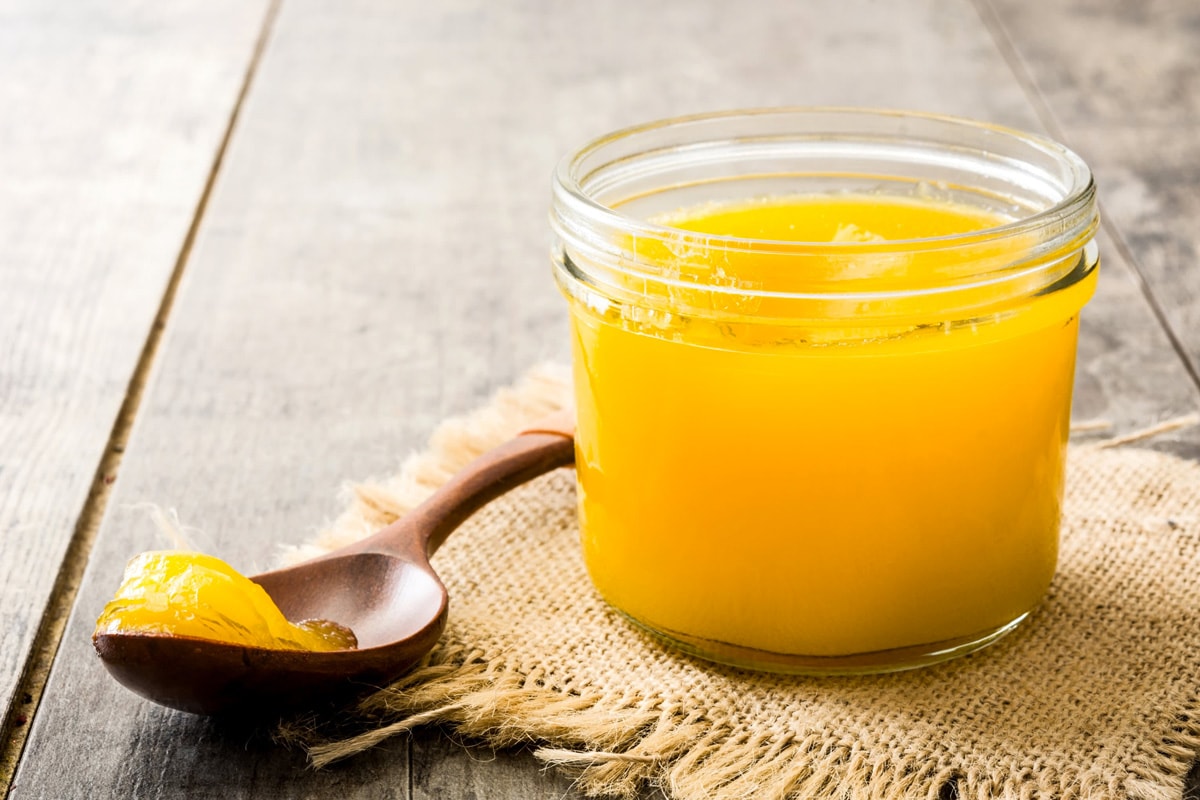Close look of clarified butter near a wooden spoon with ghee butter.