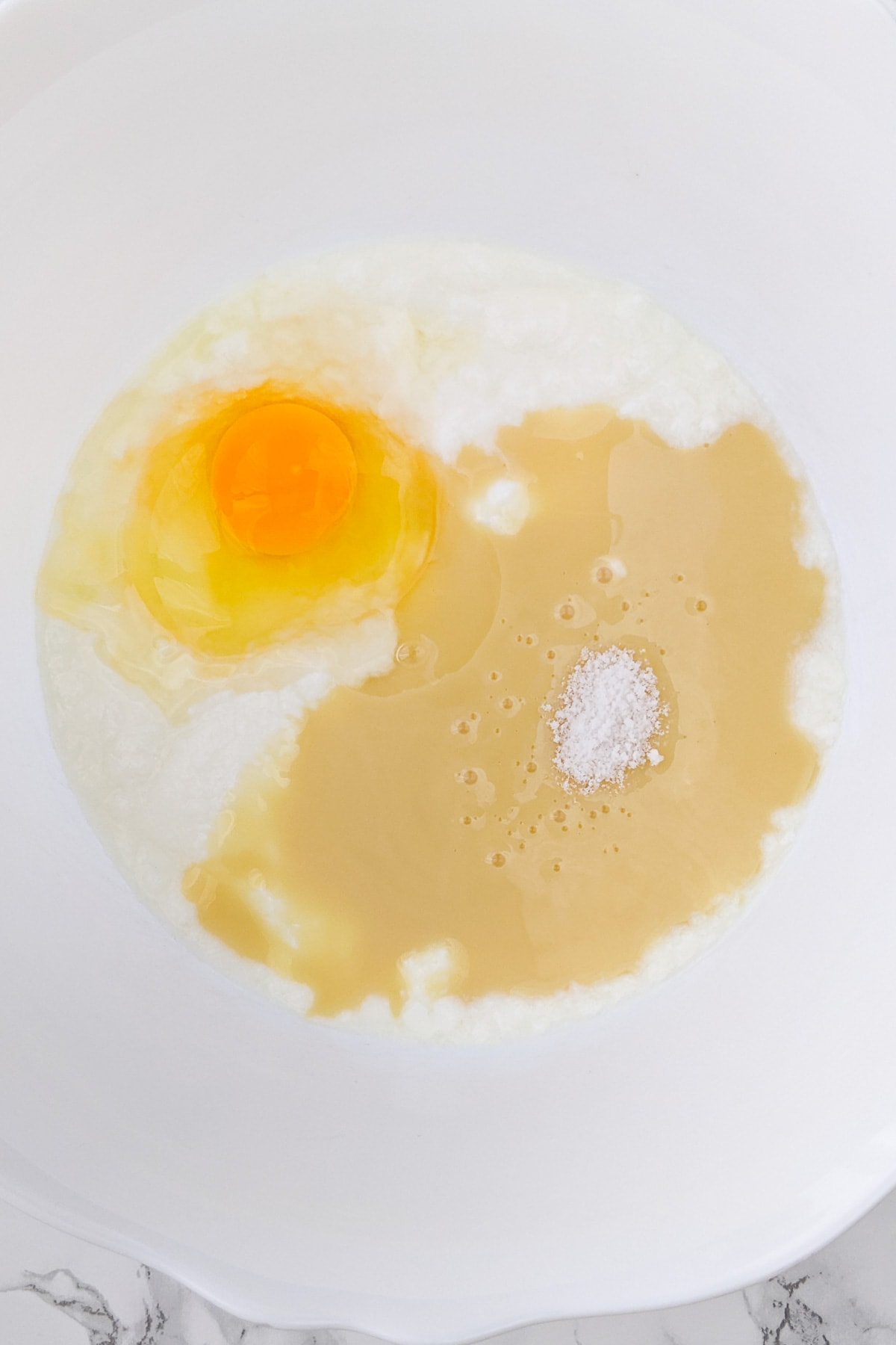 Top view of a deep bowl with yogurt, condensed milk and an egg.