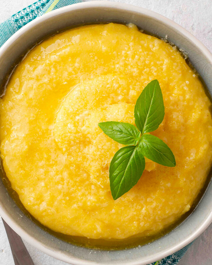 Top view of a vintage plate with polenta and a brunch of basil.