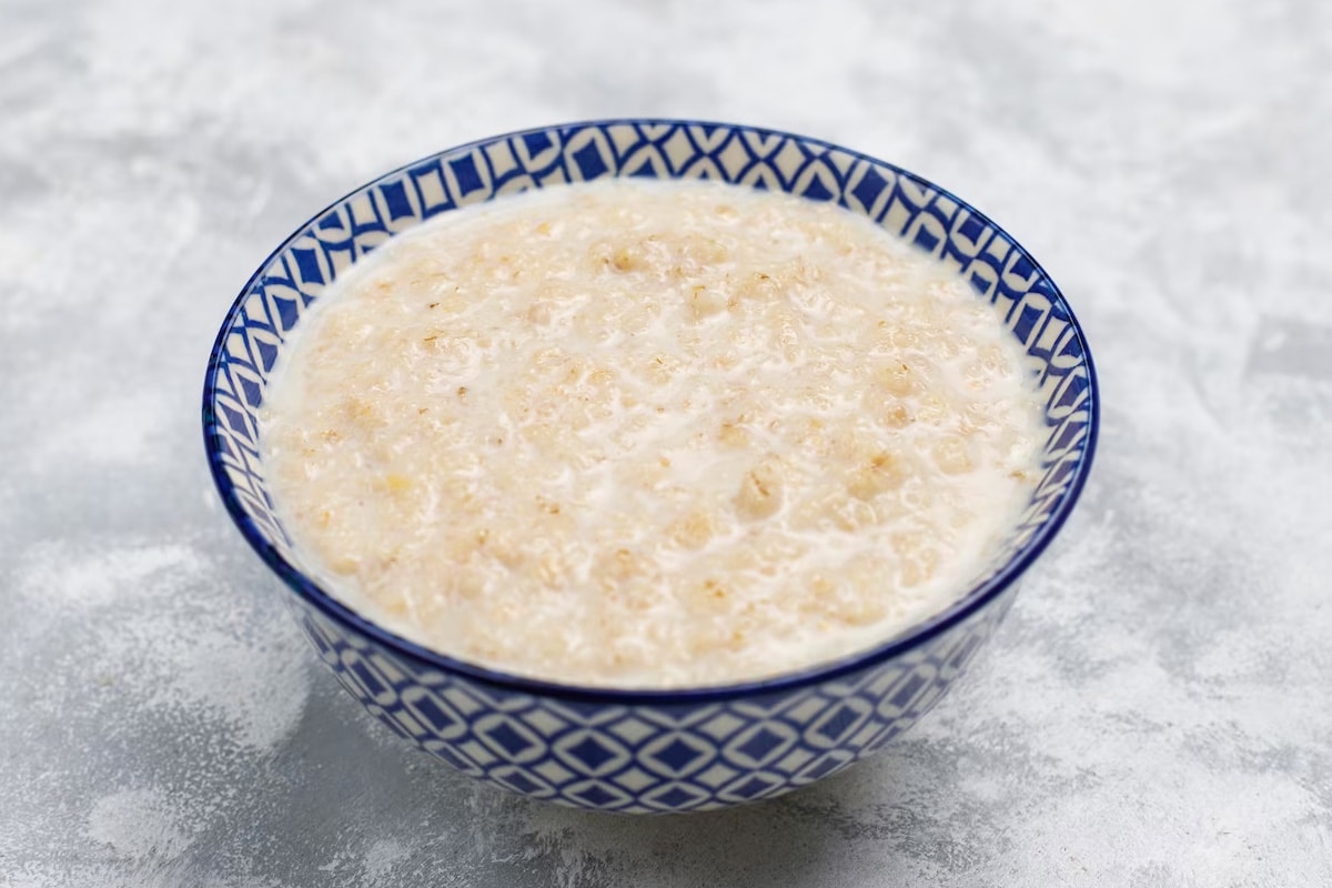 A white and blue plate with ornaments that is filled with porridge.