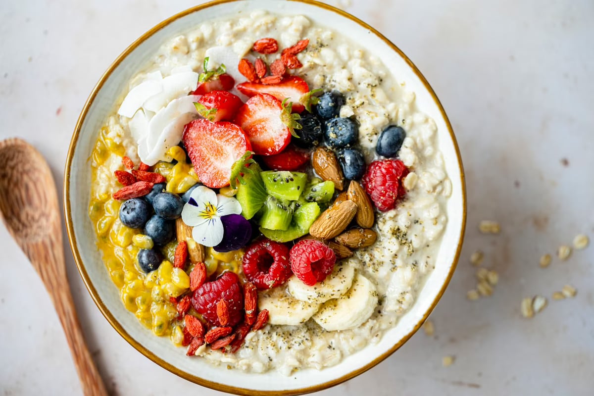 Top look of a plate with porridge, nuts and different fresh fruits.