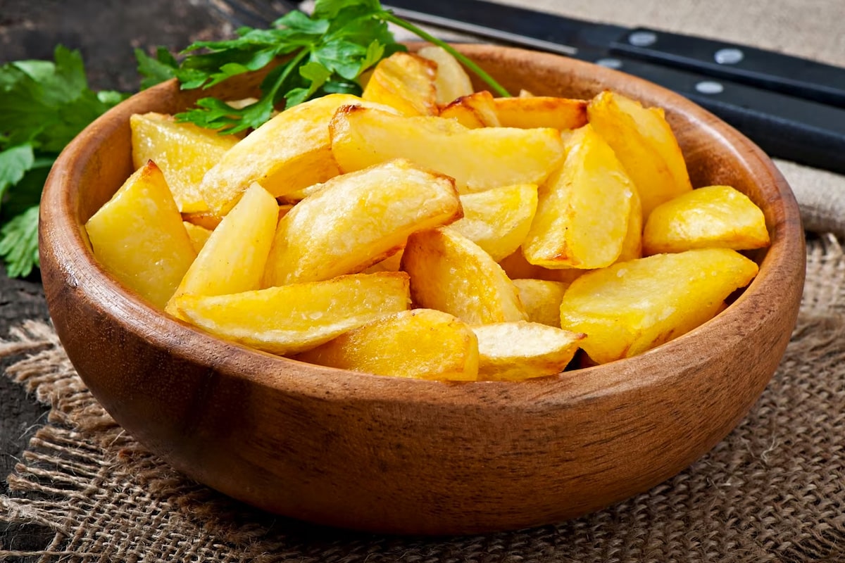 Roasted potato wedges that are served in a wooden bowl.