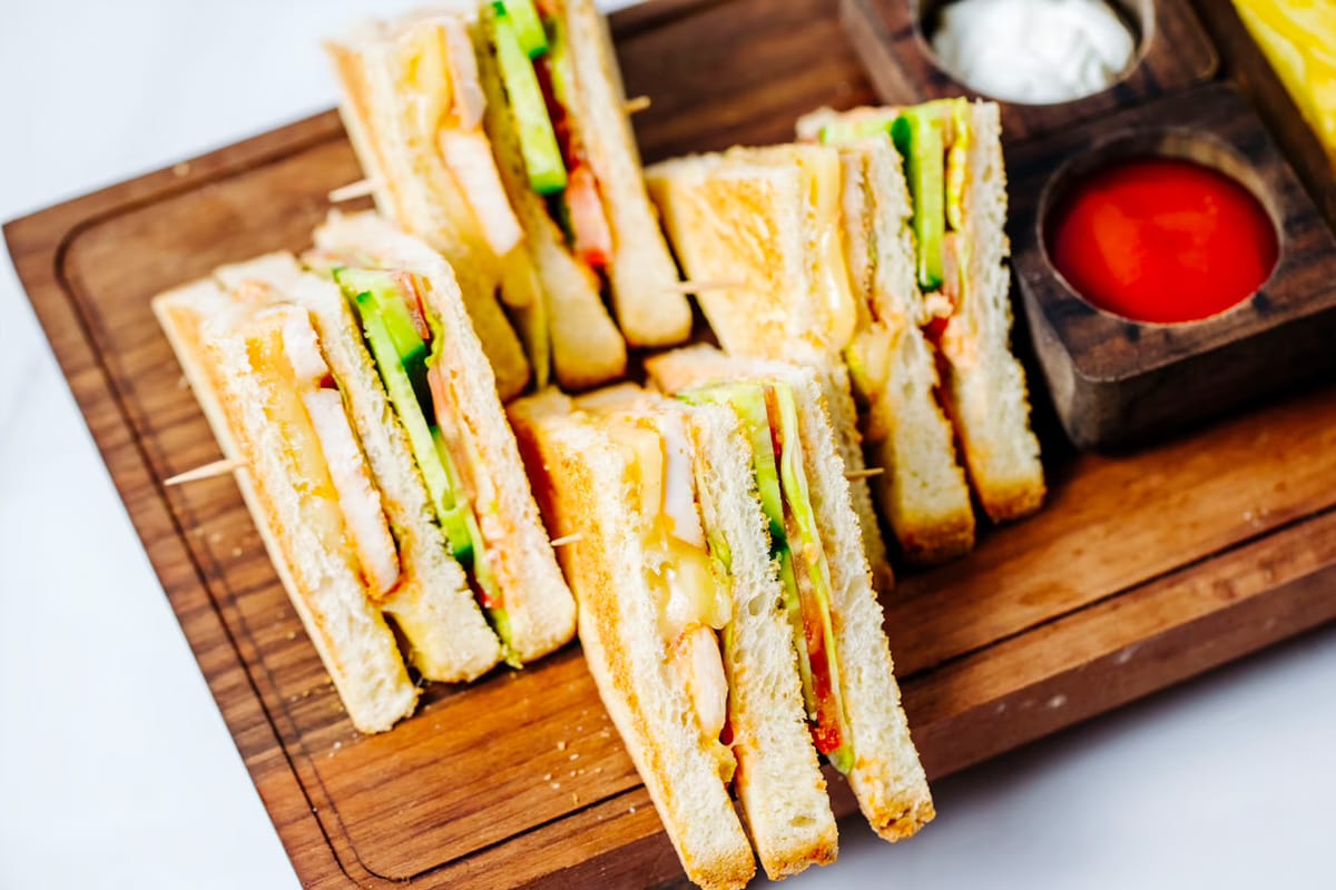 Finger sandwiches served on a wooden cutting board.