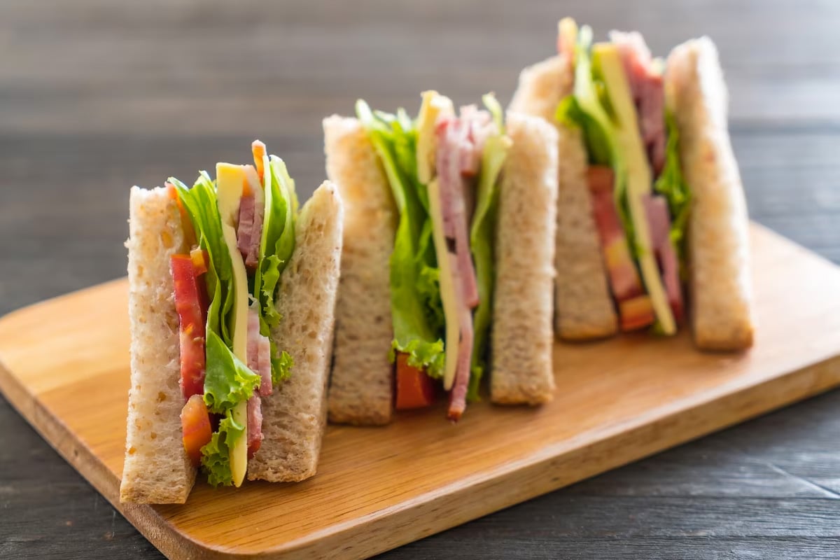 3 singer sandwiches served on a wooden board.