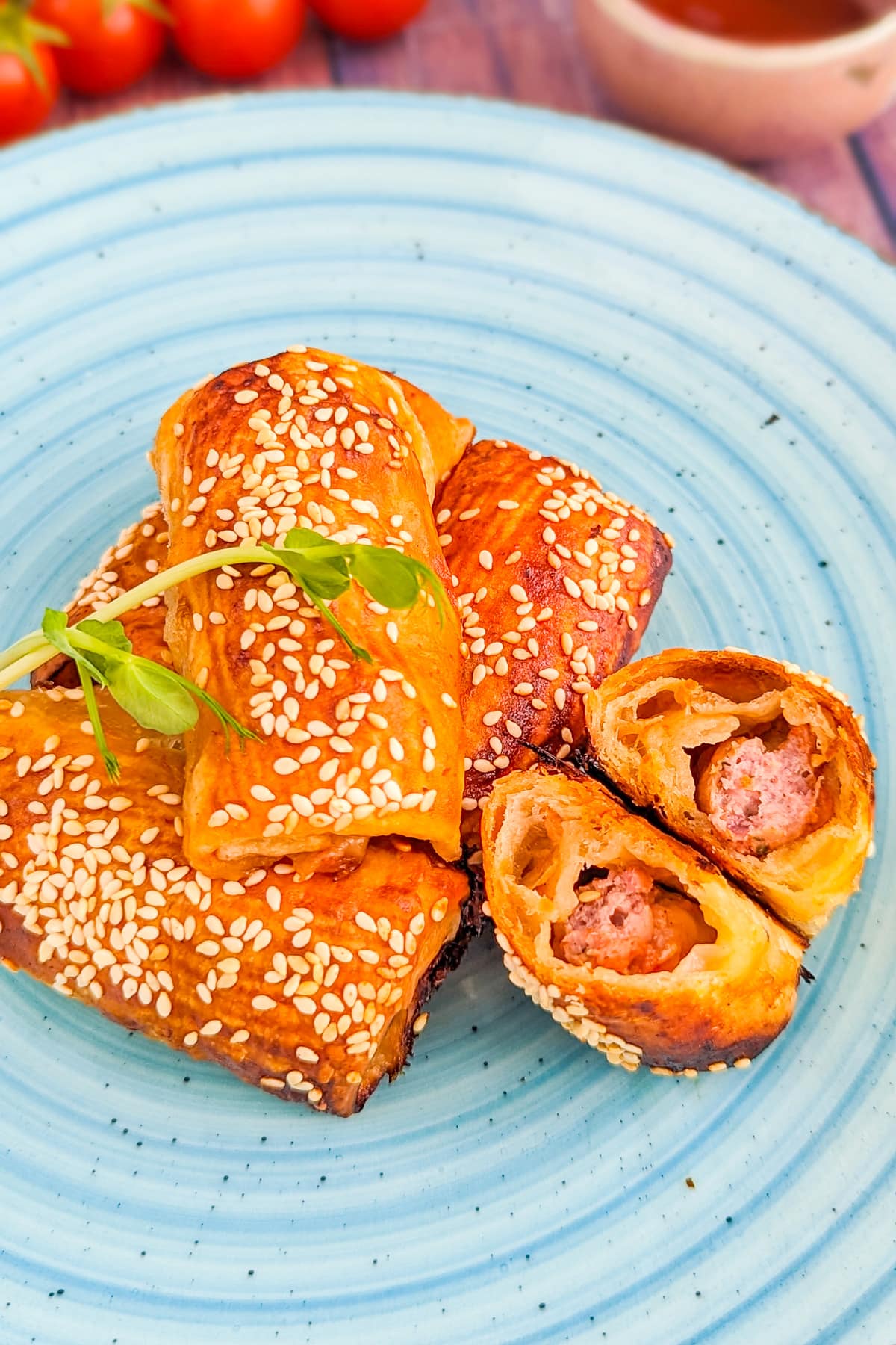 Close look of sesame sausage rolls on a blue plate.