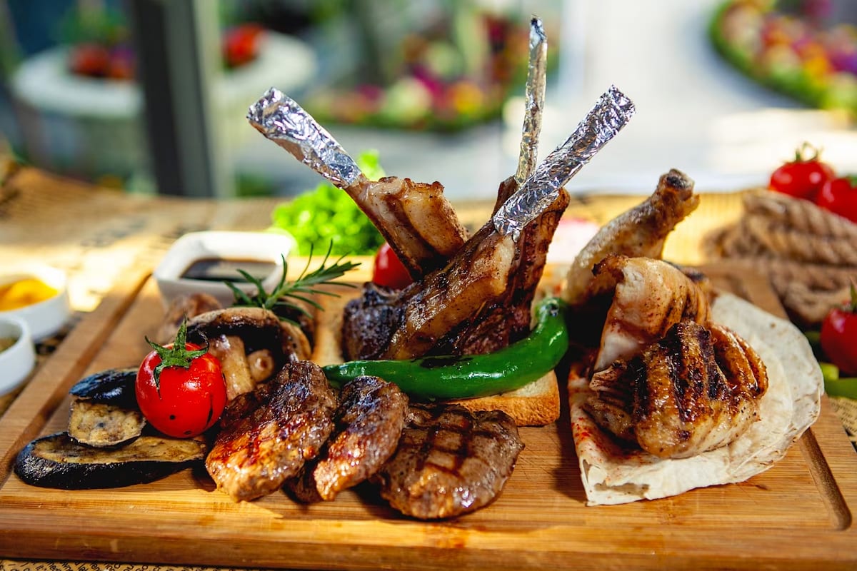 Roasted lamb with vegetables on a wooden board.