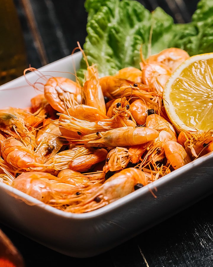 Close look of oven-baked shrimp with half of the fresh lemon.
