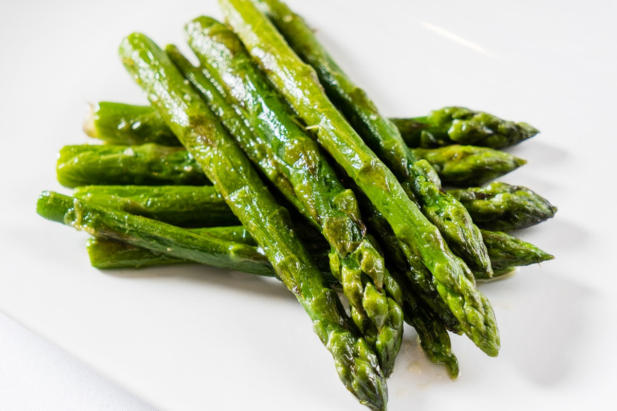 Close view of fried asparagus on a white plate.