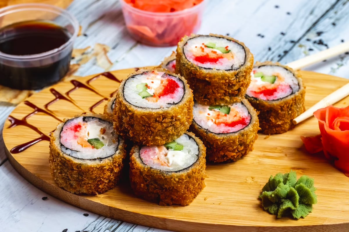Fried sushi rolls on a wooden serving board.