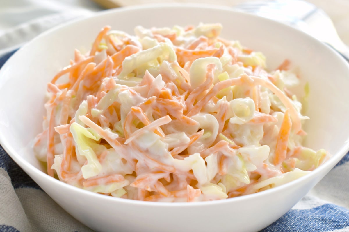 A white plate with coleslaw salad in it.