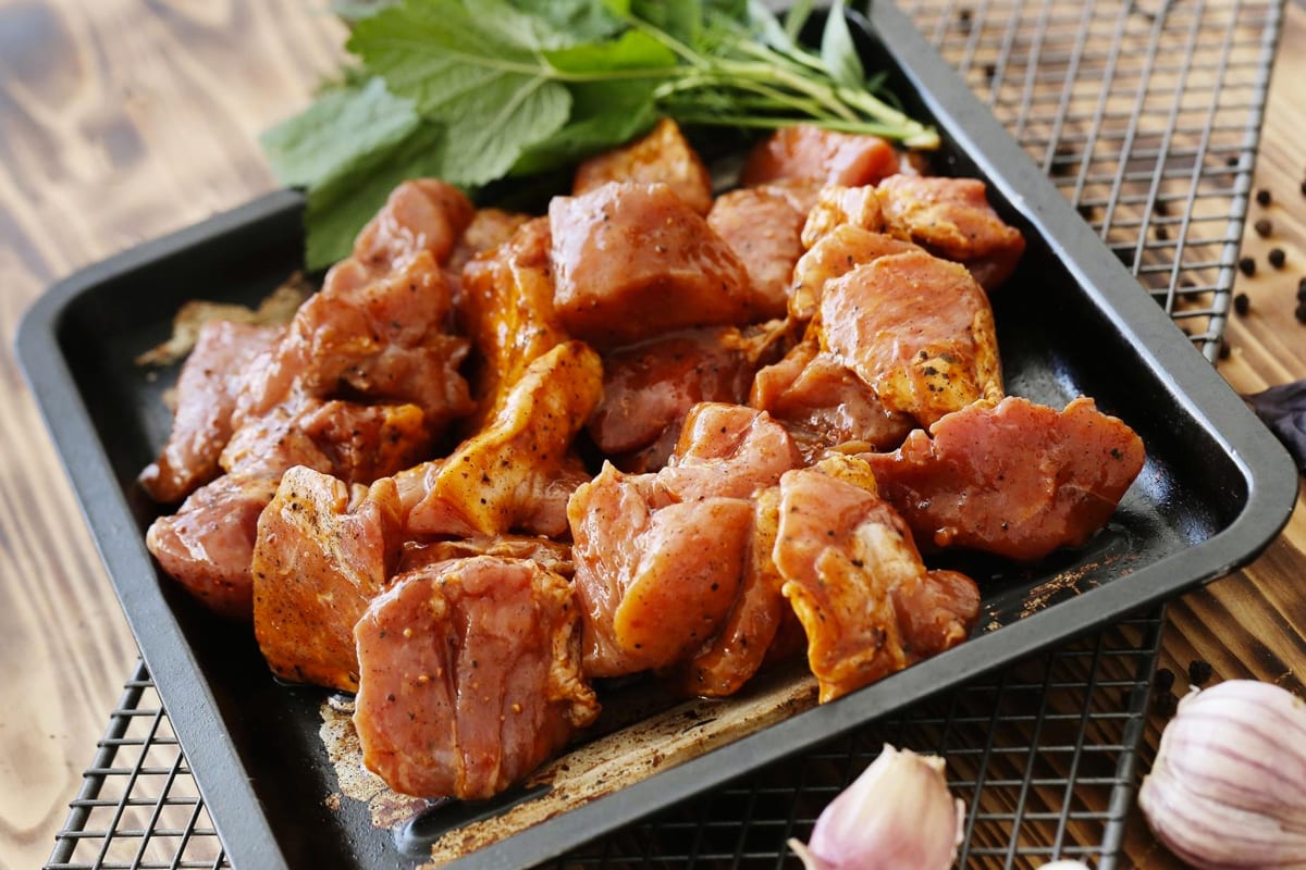 Close look of marinated chicken pieces in a traybake.