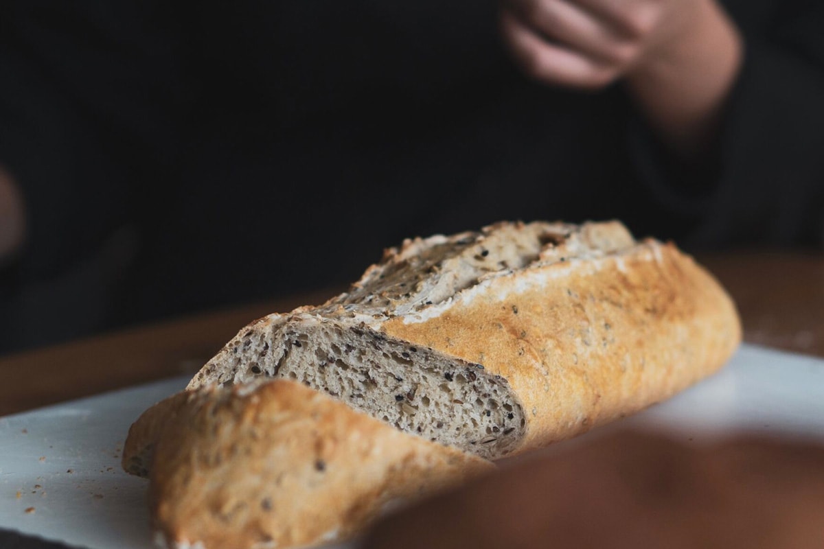 A fresh baguette close look with a man hand in the background.