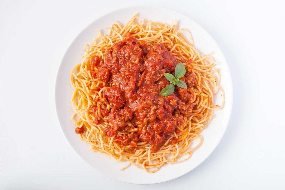 White plate with bolognesse spaghetti pasta isolated on a white background.