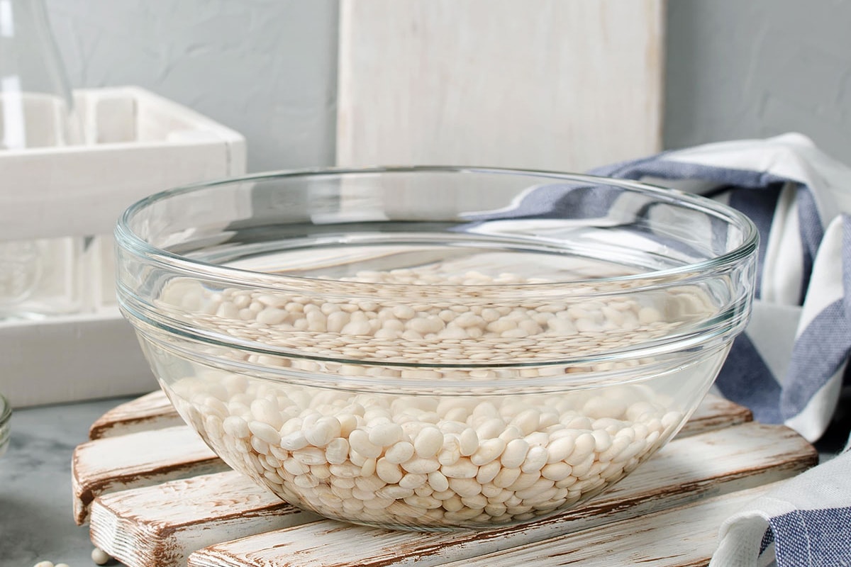 Soaking white beans in a transparent bowl with water.