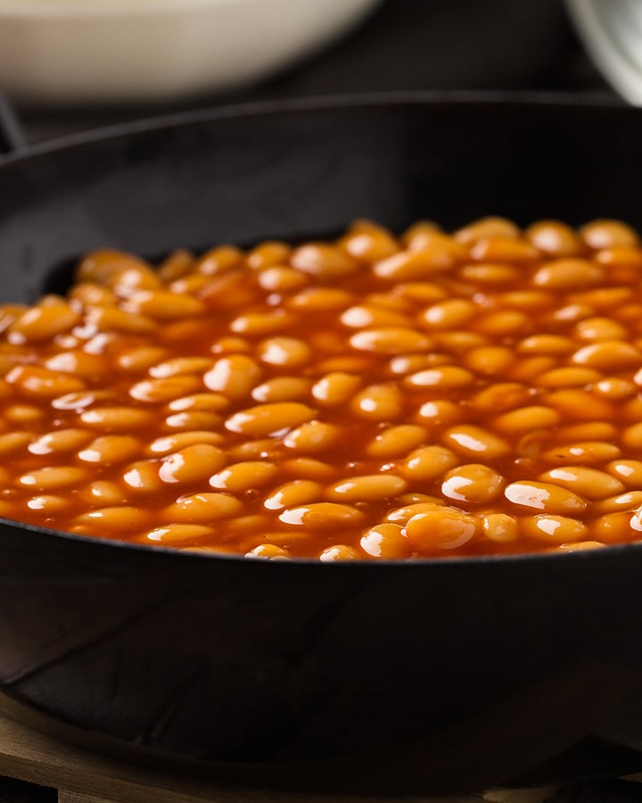 Close look of cooked beans in a black saucepan.