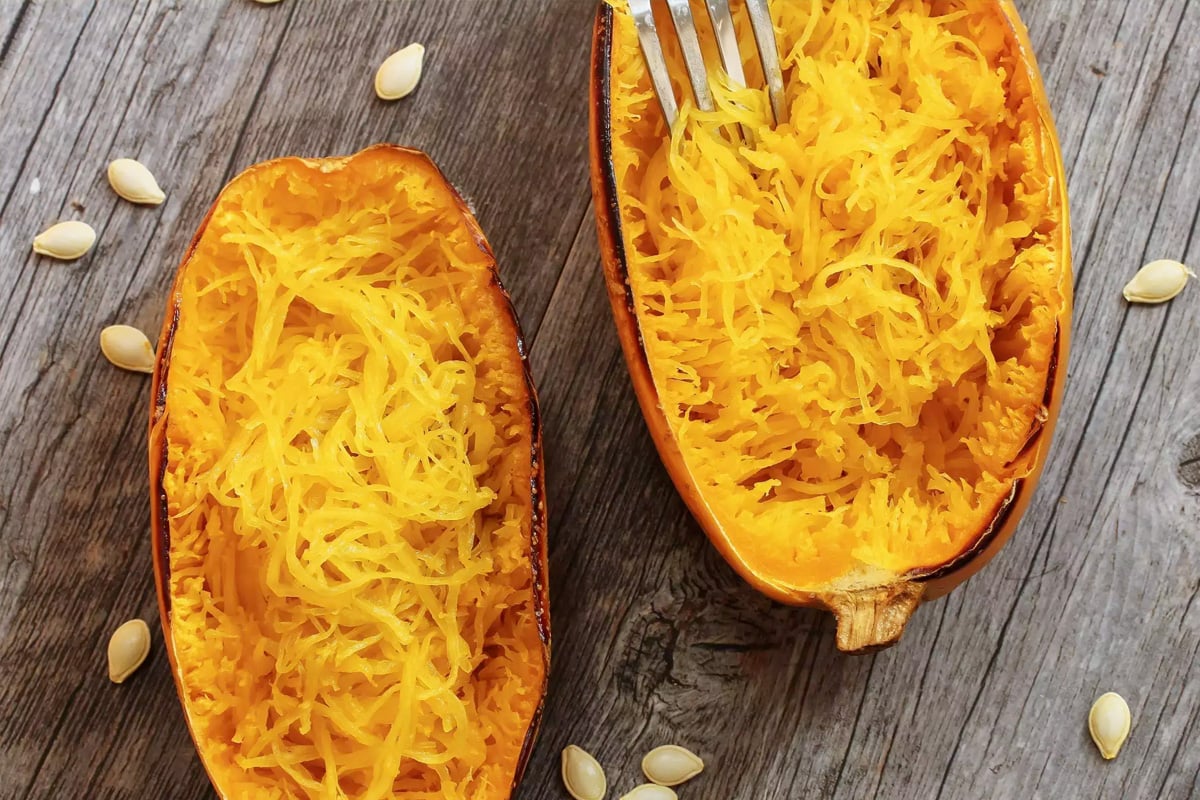 Top view of two halves of baked spaghetti squash with a fork in it.