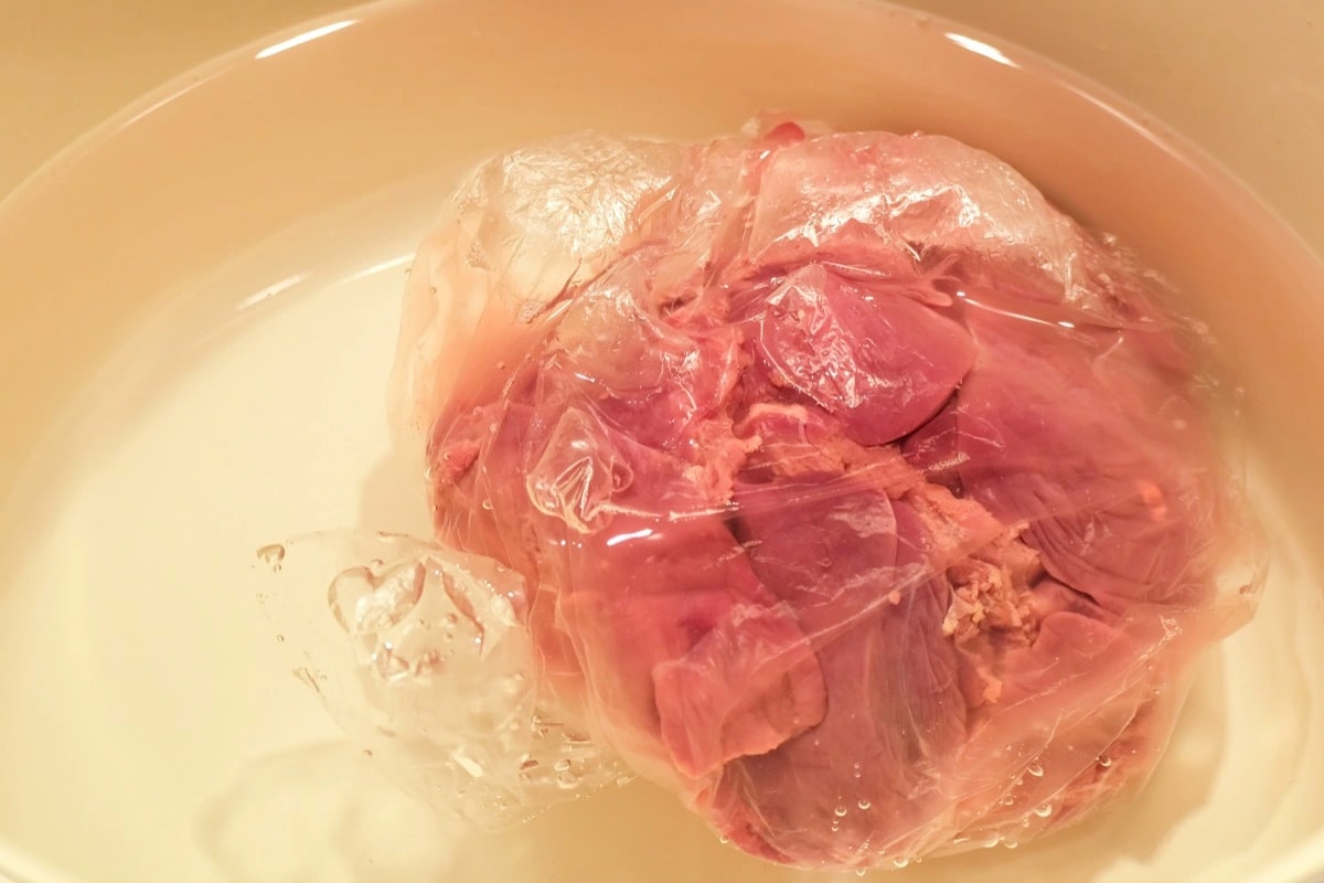 Close look of thawing chicken meat in cold water.
