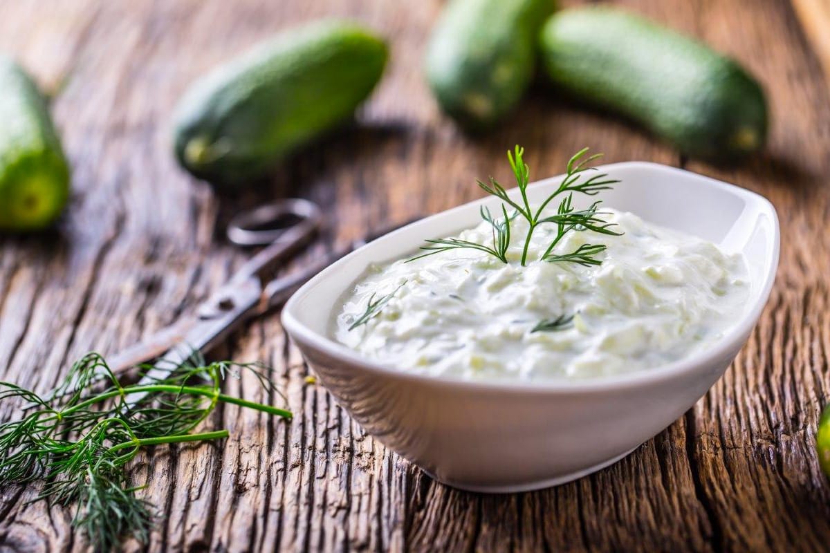 A white sauce plate with tzatziki sauce and fresh dill.