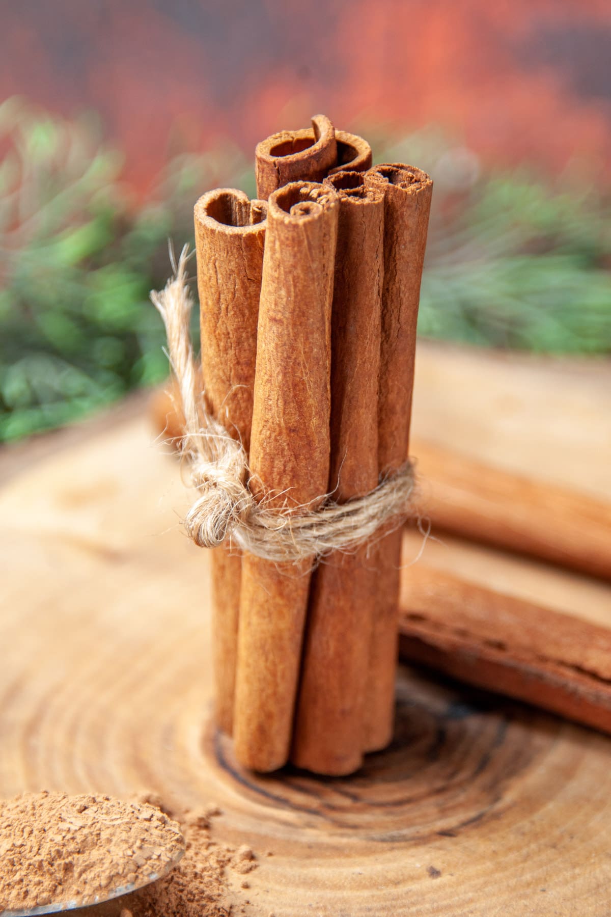 5 cinnamon sticks with a rope sitting on a wooden plate.
