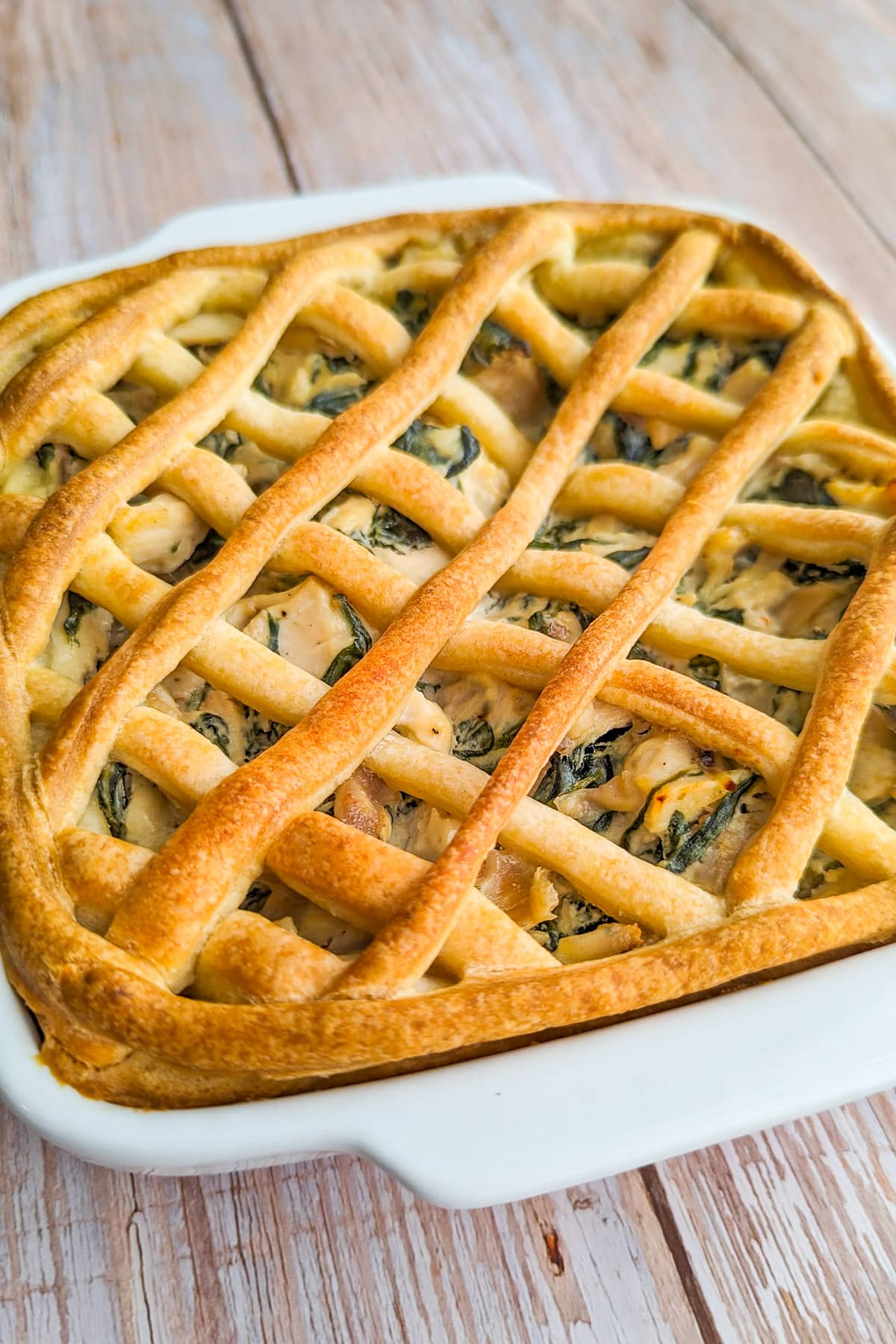 Chicken pie with spinach and chicken on a wooden table.