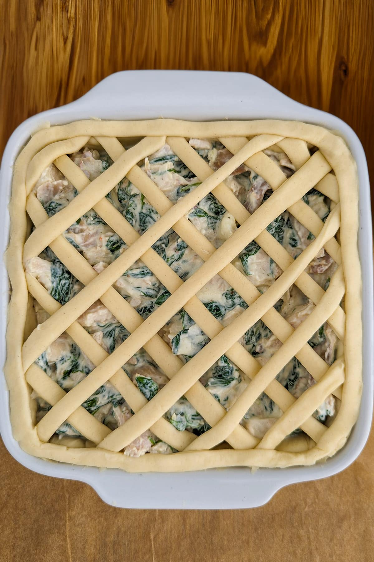 Top view of spinach and chicken pie on a wooden table.