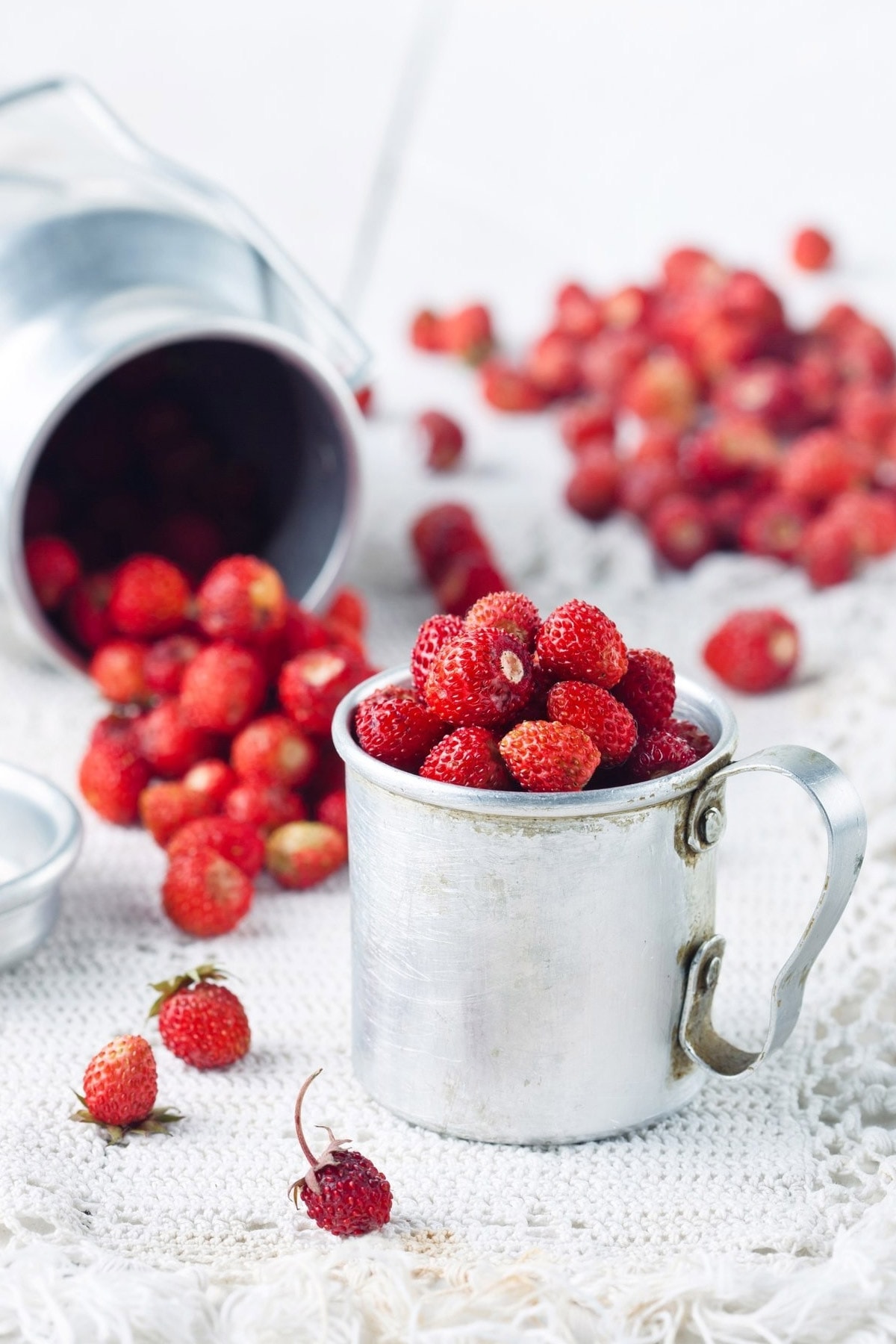 Close look of a metal cup with wild strawberries.