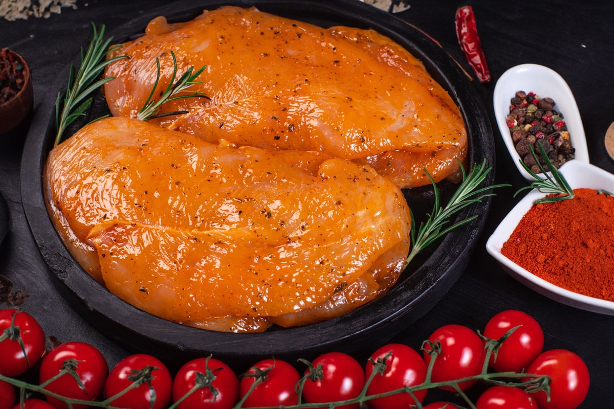 Marinating turkey breasts near paprika and cherry tomatoes.