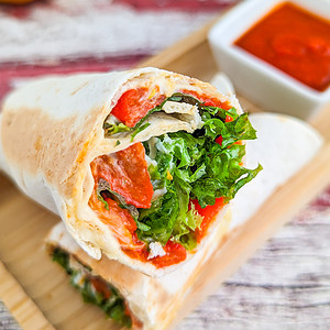 Close look of veggie wrap with roasted bell peppers and salad leaves.