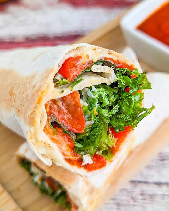 Close look of veggie wrap with roasted bell peppers and salad leaves.