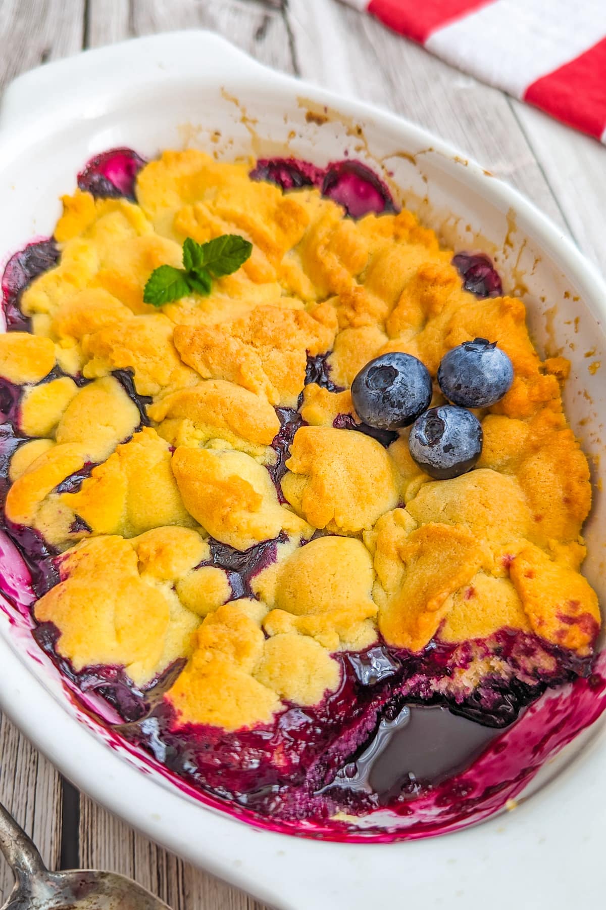Top view of a white baking dish with blueberry cobbler in it.
