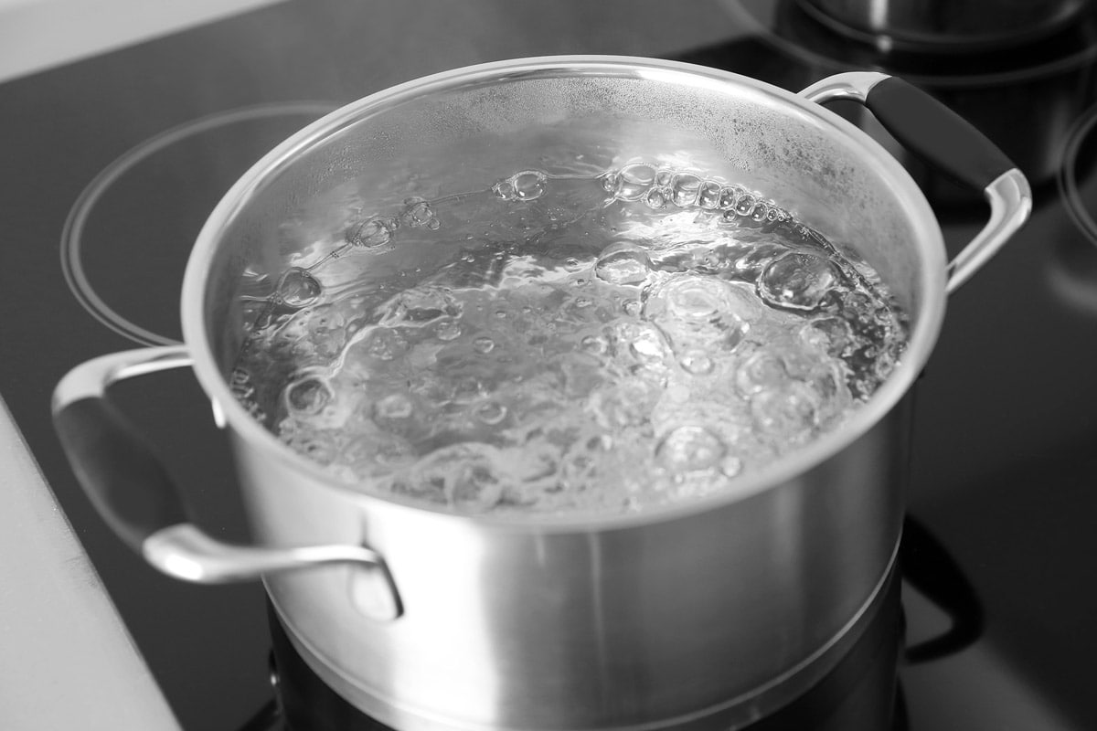 Top view of a metal pan with boiling water in it.