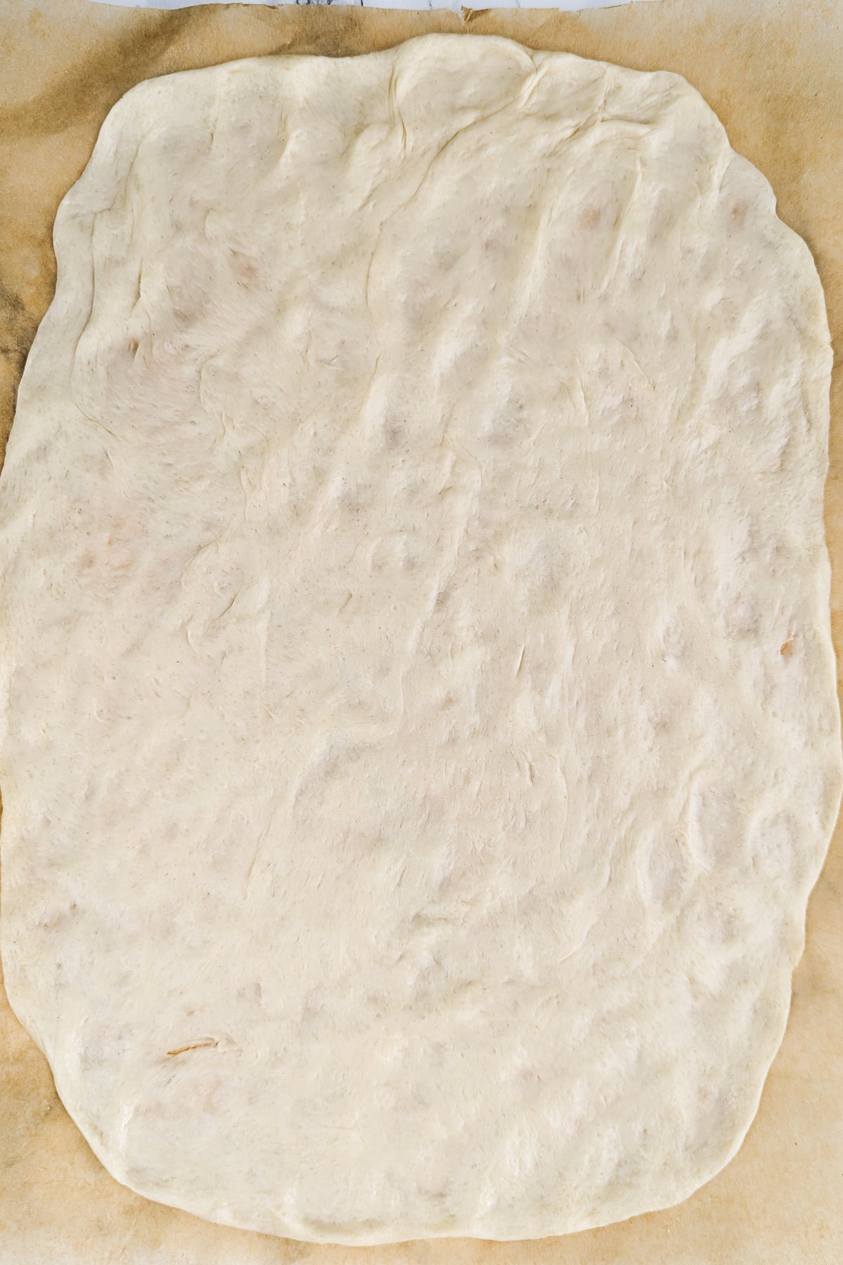 Top view of a dough layerd on a parchment baking paper.