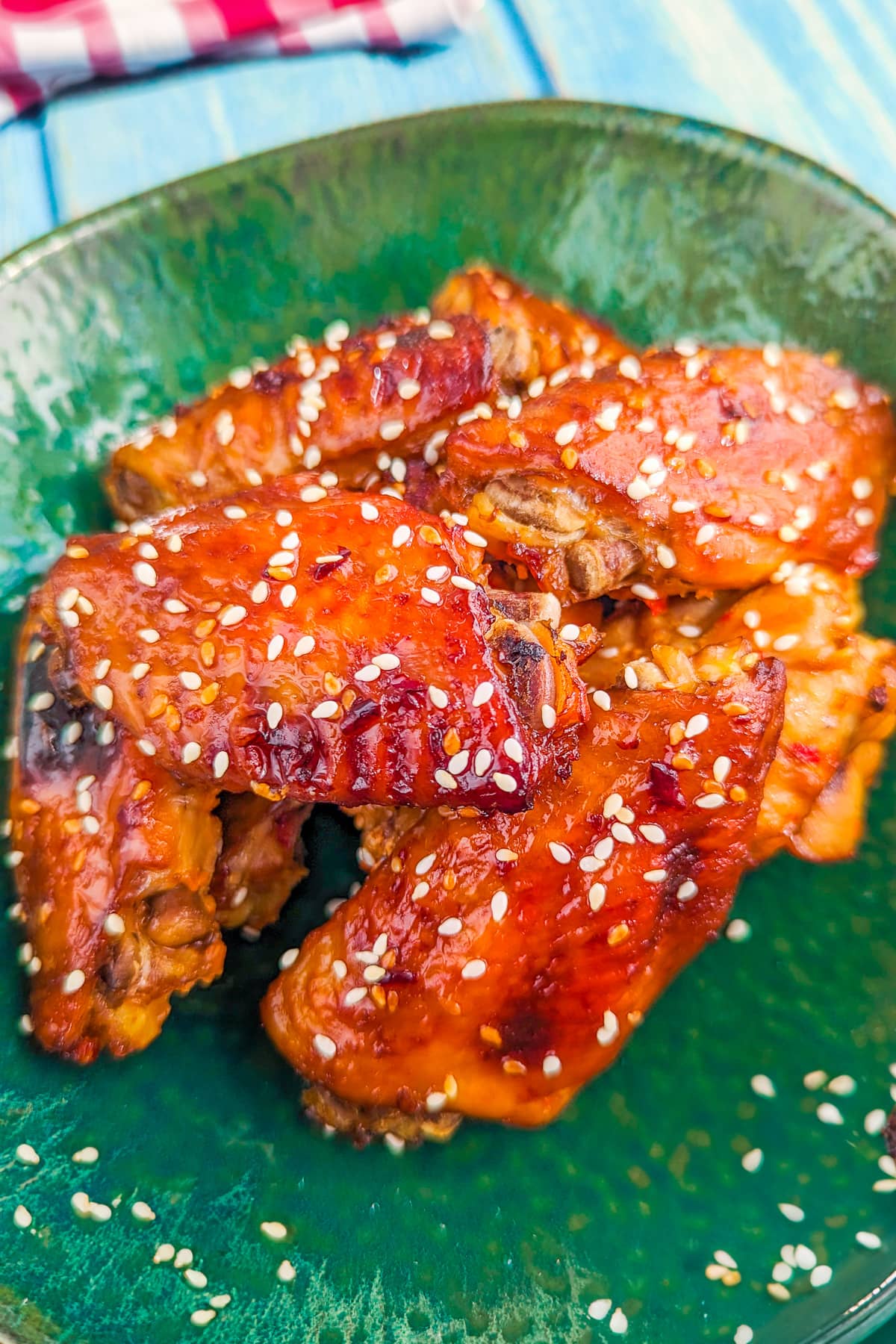 Close look of chicken wings with sesame seeds in a green plate.