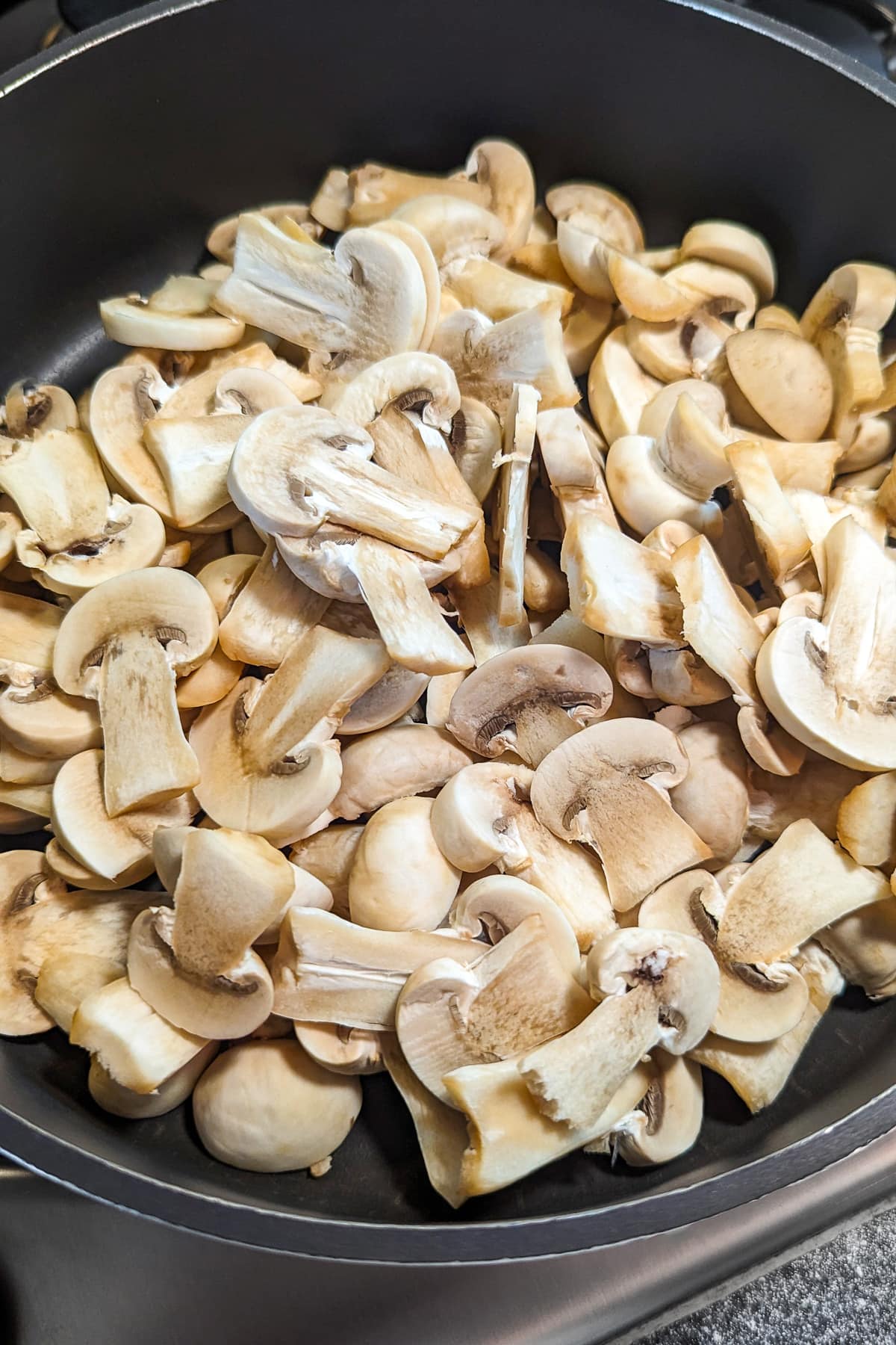 Pan with mushrooms halves on the stove.