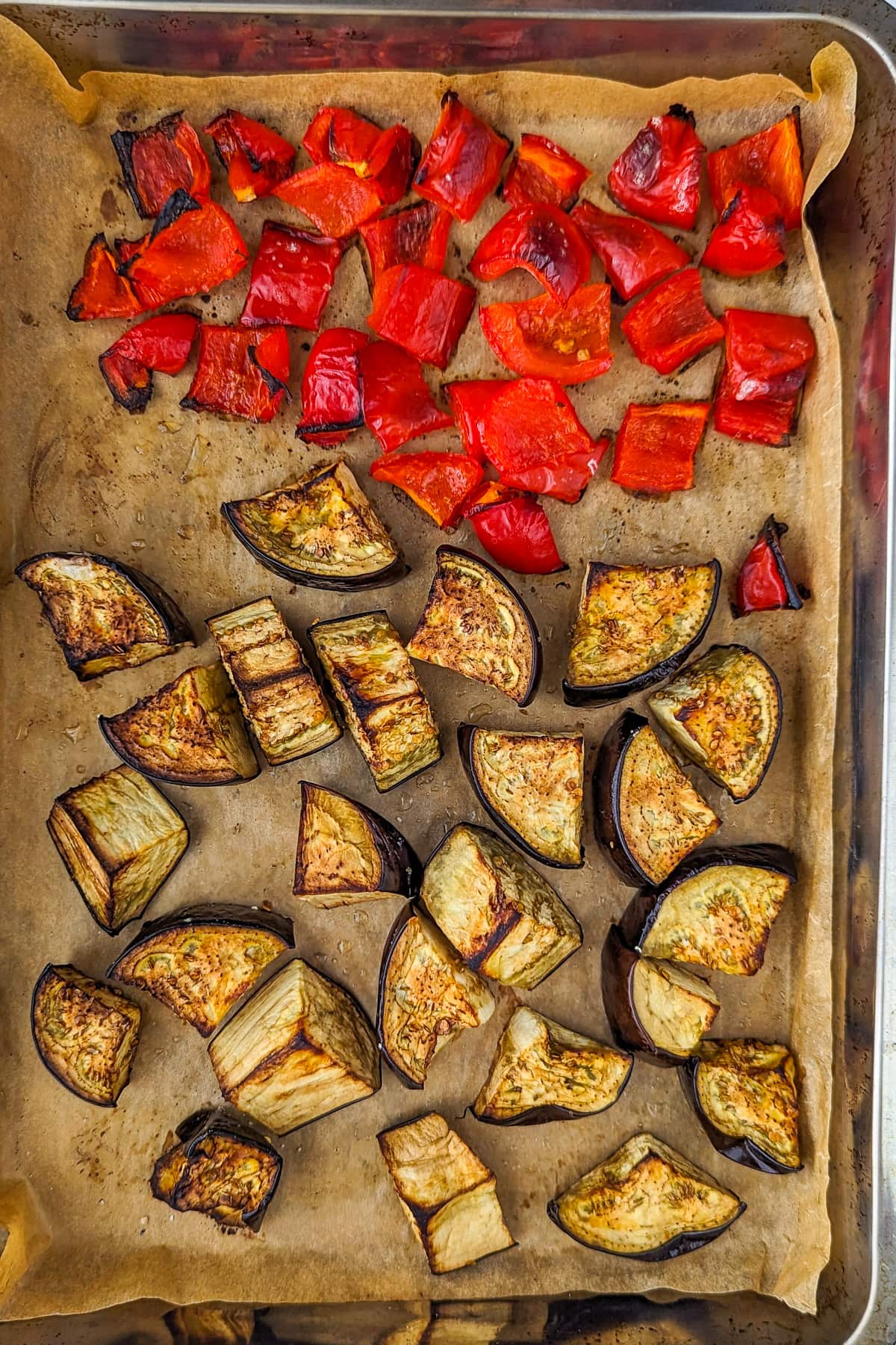 Top view of a baking traybake with roasted eggplants and bell peppers.