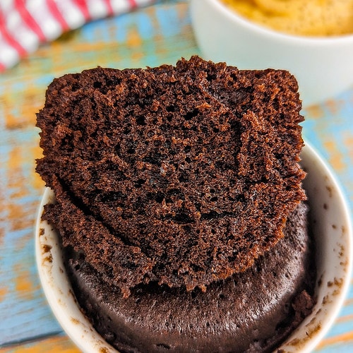 Close look of a mug with baked chocolate cake in the microwave.